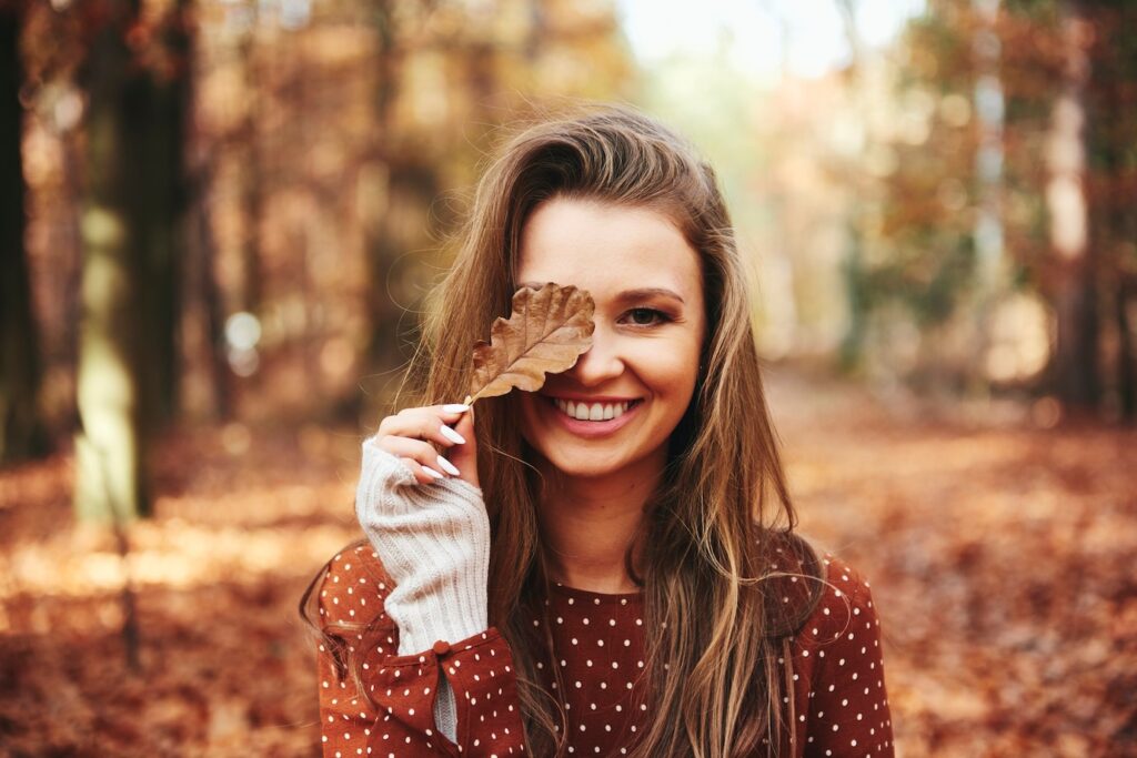 donna copre occhio foglia in autunno
